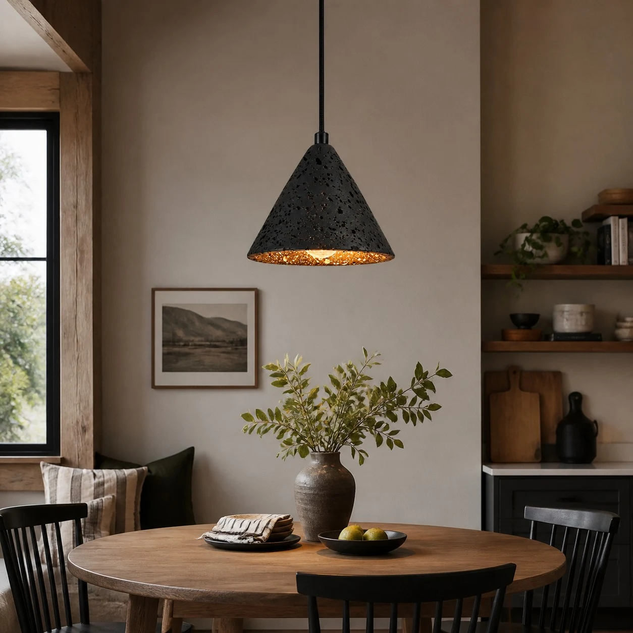 Hanglamp van zwart lavasteen boven een eettafel van warm hout.